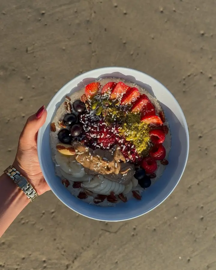 A hand holding the Sante Organics signature bowl above the sand, seen from above
